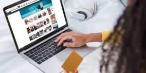 cropped image of woman holding credit card and using laptop with amazon on screen