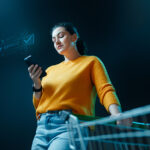 Mujer comprando online desde el smartphone con un carrito de la compra.