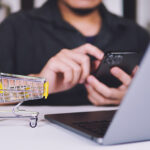 Persona usando el smartphone y el portátil para comprar online.